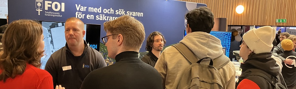 Besökare på en studentmässa framför FOI monter