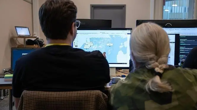 Två deltagare i övningen Safe cyber sitter framför en datorskärm. Foto: FOI